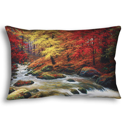 A throw pillow designed with a painting of a river through an autumn forest, with red and yellow trees and an orange, leaf-coated ground.