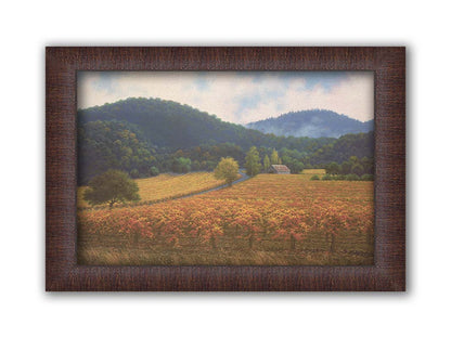 A painting of expansive vineyard fields, turned yellow, red, and orange for the fall. Rolling hills of forests fill the background. Printed on canvas and framed.