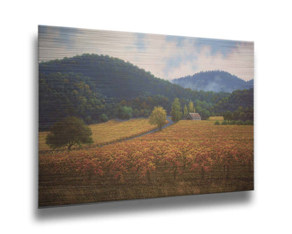 A painting of expansive vineyard fields, turned yellow, red, and orange for the fall. Rolling hills of forests fill the background. Printed on metal.