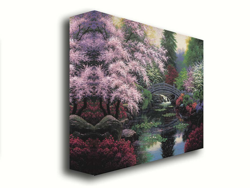 A painting of a tranquil pond surrounded by pink, red, and green flowered trees and shrubs. Lilly pads and fallen pink blossoms float on the water, which is crossed by a wooden bridge. Printed on canvas.