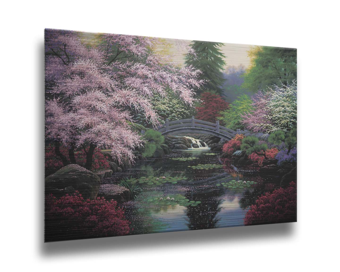 A painting of a tranquil pond surrounded by pink, red, and green flowered trees and shrubs. Lilly pads and fallen pink blossoms float on the water, which is crossed by a wooden bridge. Printed on metal.