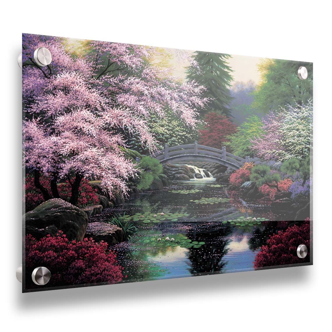 A painting of a tranquil pond surrounded by pink, red, and green flowered trees and shrubs. Lilly pads and fallen pink blossoms float on the water, which is crossed by a wooden bridge. Printed on acrylic.