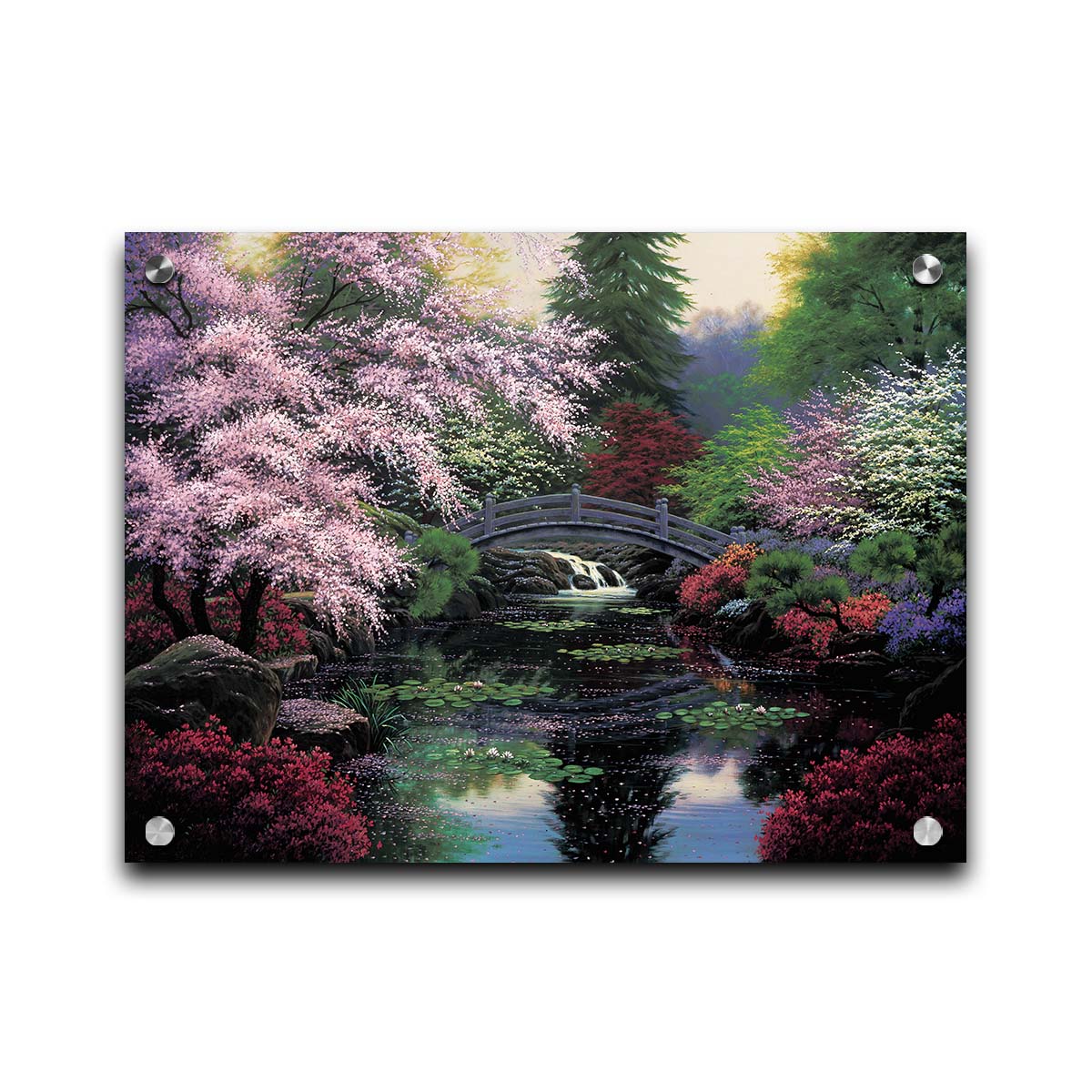 A painting of a tranquil pond surrounded by pink, red, and green flowered trees and shrubs. Lilly pads and fallen pink blossoms float on the water, which is crossed by a wooden bridge. Printed on acrylic.