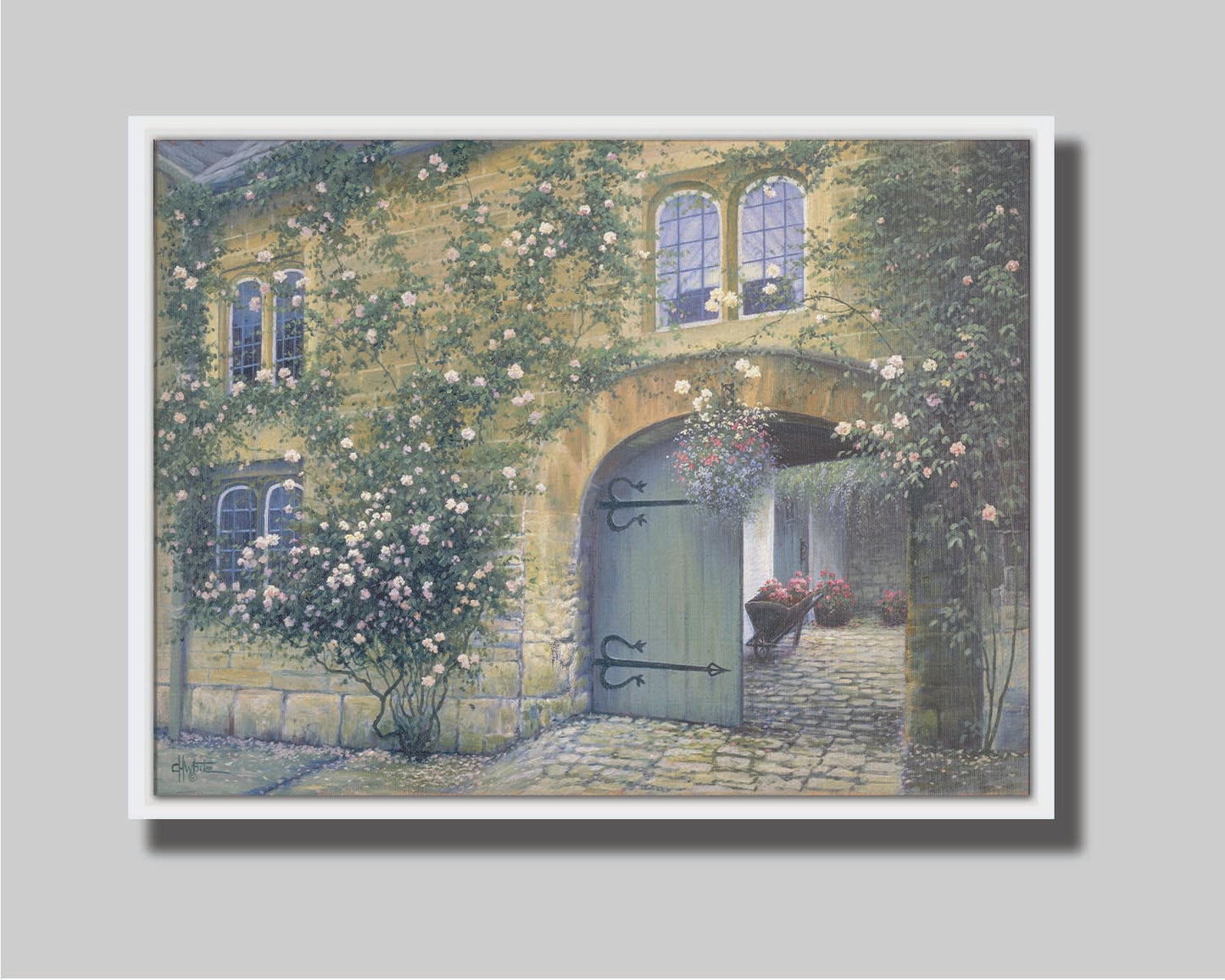 A painting of an arched doorway passing through a building into a courtyard. The building and courtyard are decorated with bushes and vines sprouting an assortment of white and red flowers. Printed on canvas in a float frame.