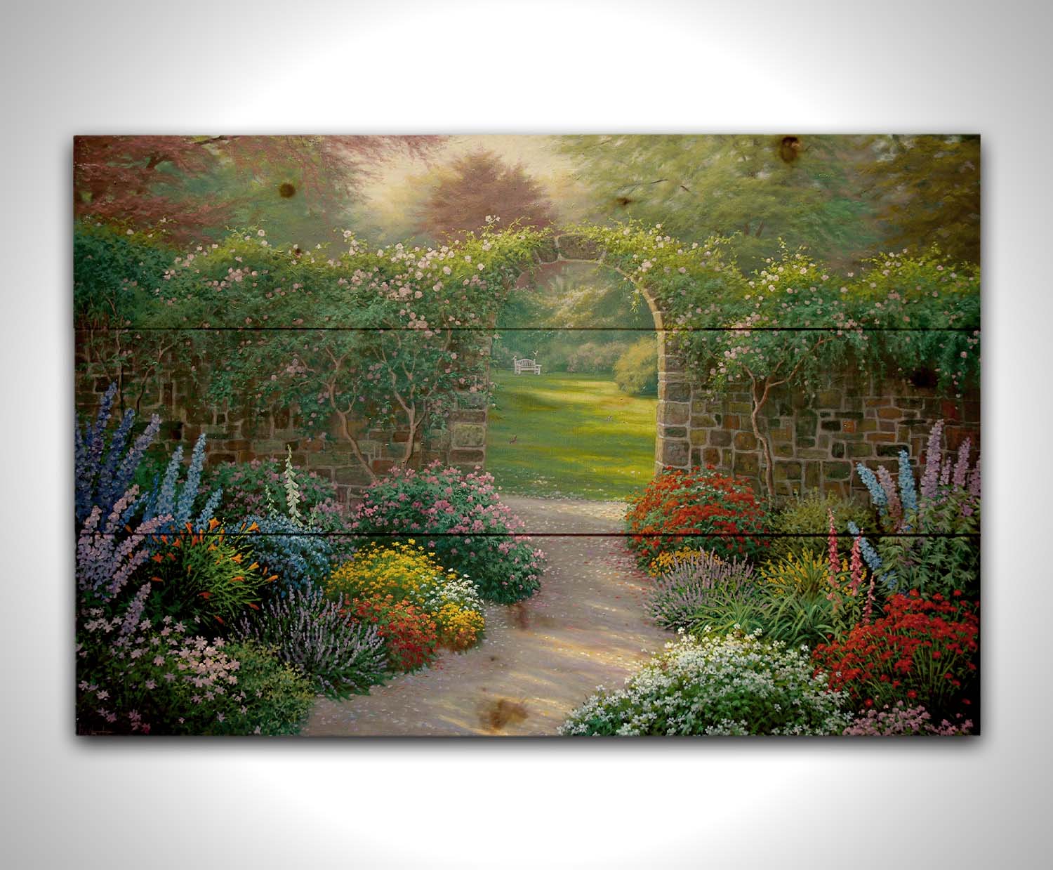 A painting of a stone walled garden with an archway leading to a grassy yard. There are flowers in all colors lining the pathway. Printed on a wood pallet.