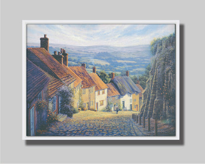 A painting looking down a cobblestone road on a hill lined with houses. A person can be seen walking down the path past flower-laden walls. Printed on canvas in a float frame.