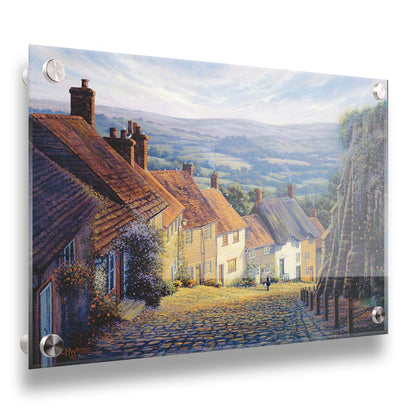 A painting looking down a cobblestone road on a hill lined with houses. A person can be seen walking down the path past flower-laden walls. Printed on acrylic.