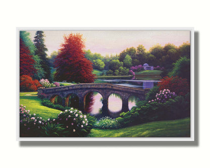 A landscape painting of a lake scene. A stone bridge in the foreground is surrounded by bushes of pink and red flowers, as well as green and red trees. Printed on canvas in a float frame.