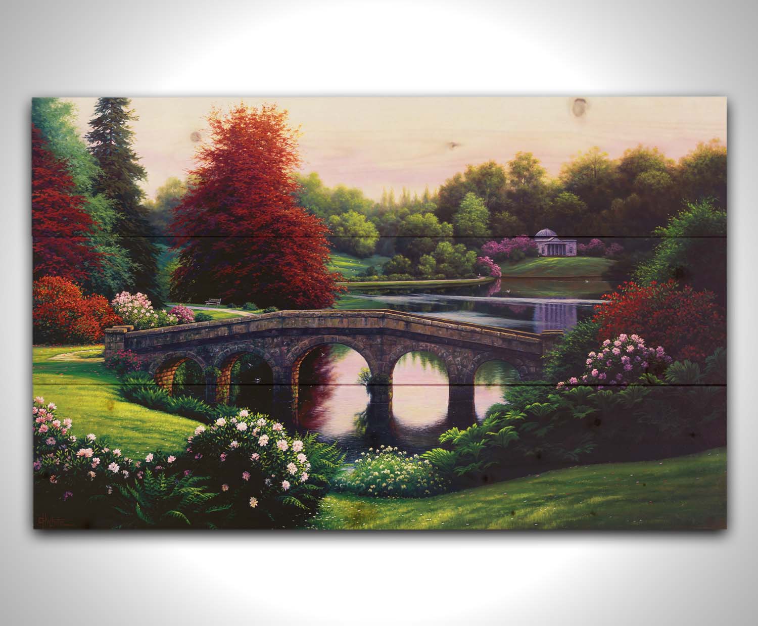 A landscape painting of a lake scene. A stone bridge in the foreground is surrounded by bushes of pink and red flowers, as well as green and red trees. Printed on a wood pallet.