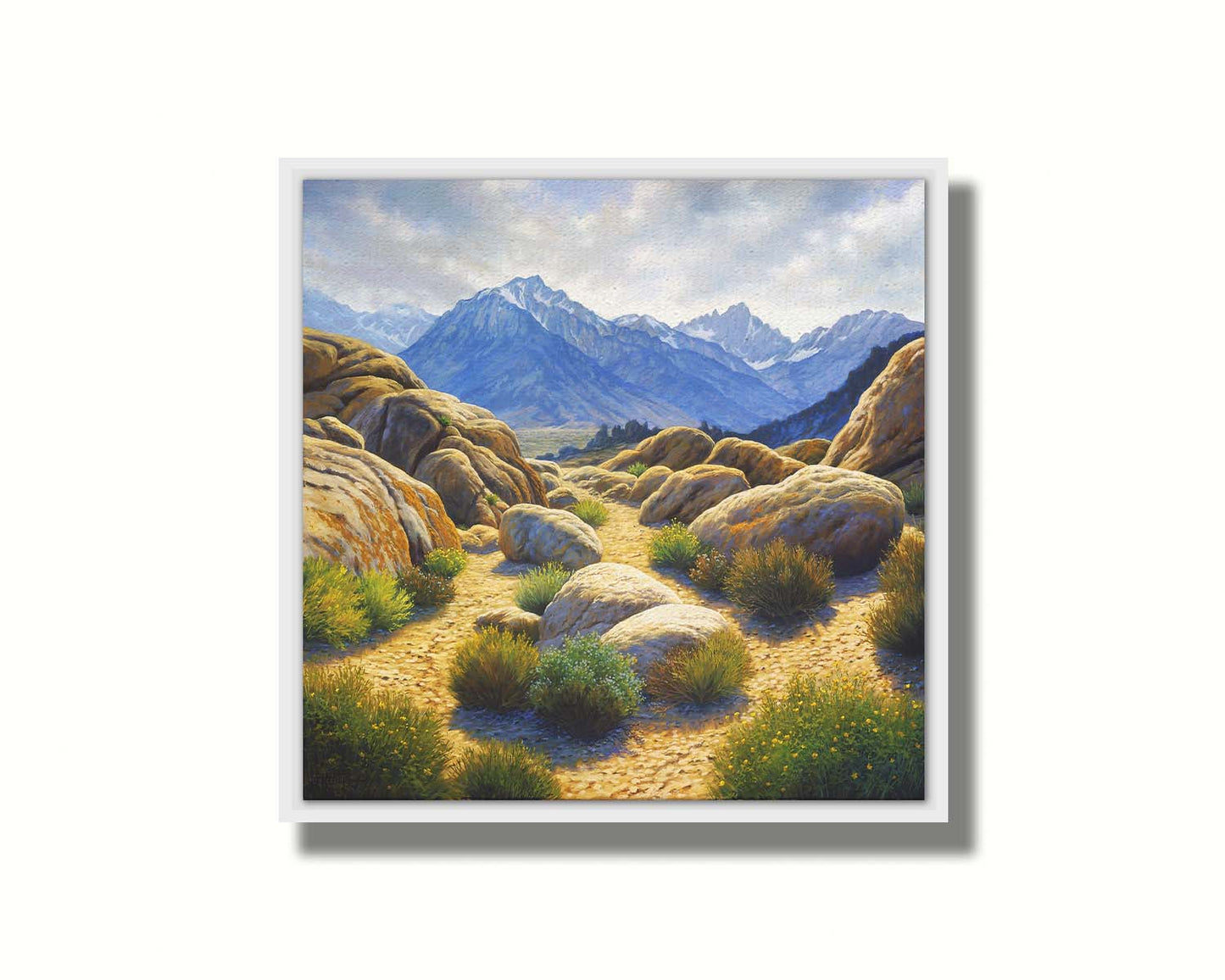 A landscape painting of Mount Whitney as seen from Lone Pine Lake, California. The highly detailed environment of tan stones directs the view to the distant mountains, tinted blue by the atmosphere. Printed on canvas in a float frame.