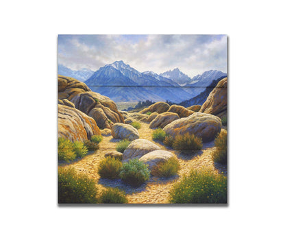 A landscape painting of Mount Whitney as seen from Lone Pine Lake, California. The highly detailed environment of tan stones directs the view to the distant mountains, tinted blue by the atmosphere. Printed on a box board.