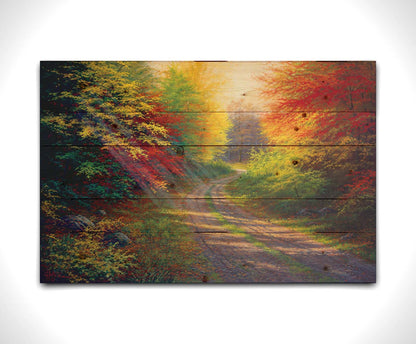 A landscape painting of a gravel road winding thorugh an autumn forest with a mix of vibrant red, yellow, and green leaves. Printed on a wood pallet.