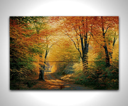 A painting of a path through an autumn forest, with sunlight highlighting the golden yellow and orange leaves of the trees. Printed on a wood pallet.