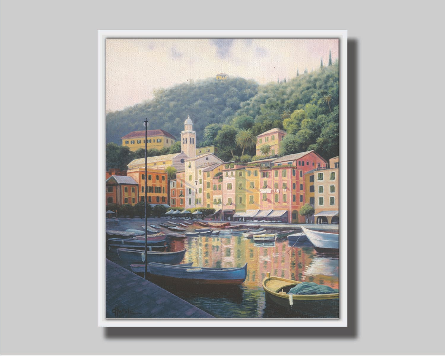 A painting of the colorful fishing town of Portofino. Many small boats are docked in the waters in the foreground, and the steep hills in the background are lush with trees. Printed on canvas in a float frame.