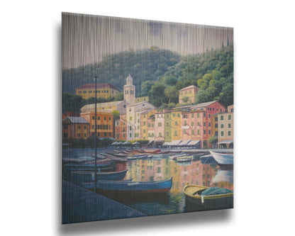 A painting of the colorful fishing town of Portofino. Many small boats are docked in the waters in the foreground, and the steep hills in the background are lush with trees. Printed on metal.