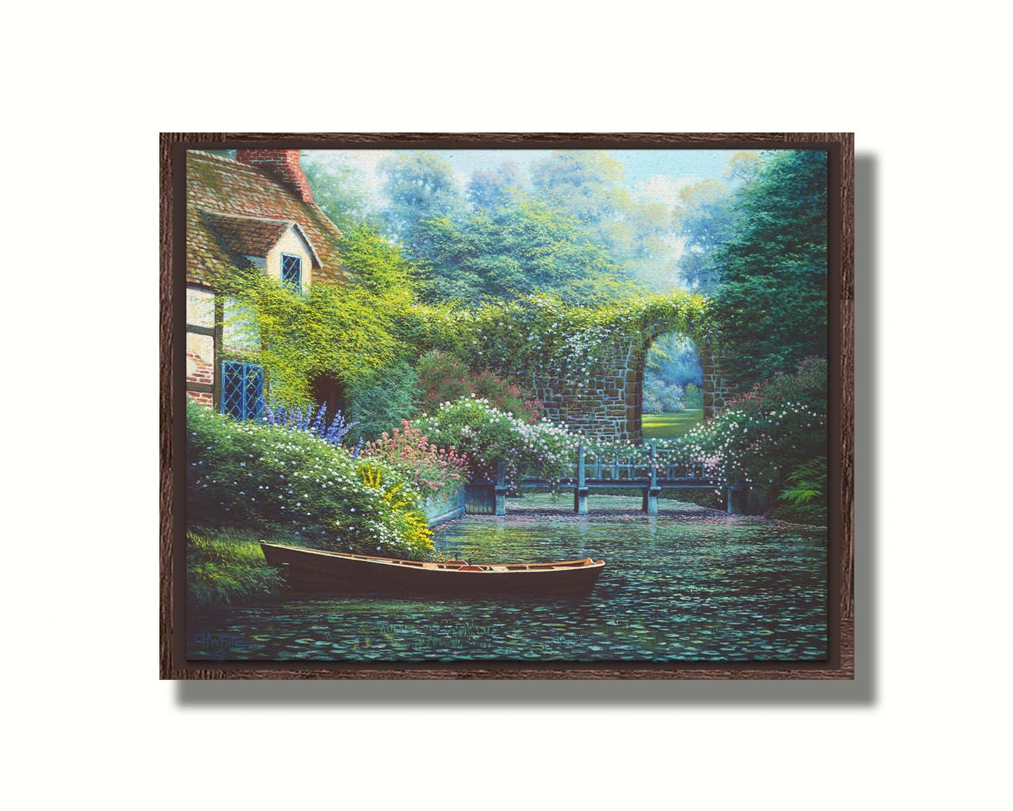 A painting of a canoe docked in a river covered in lily pads. A flower-covered bridge crosses the river, leading to a house coated in vines. A stone arched wall leads to another section of the garden in the background. Printed on canvas in a float frame.