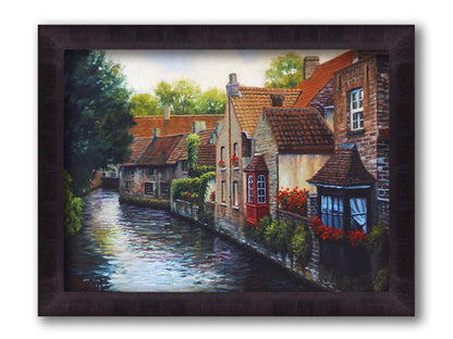 A painting of the Bruges Canal in Belgium, lined by brick homes with red and brown tlie roofs. Red flowers and a red bay window pop in the scene. Printed on canvas and framed.