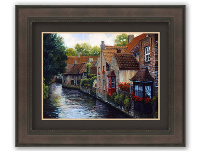 A painting of the Bruges Canal in Belgium, lined by brick homes with red and brown tlie roofs. Red flowers and a red bay window pop in the scene. Printed on paper, matted, and framed.