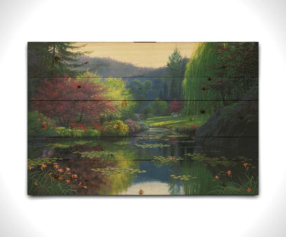 A painting of a large open garden. A pond growing lily pads fills the foreground. Bushes growing flowers in every color line the pond. A white bench sits in a grassy clearing in the background. Printed on a wood pallet.