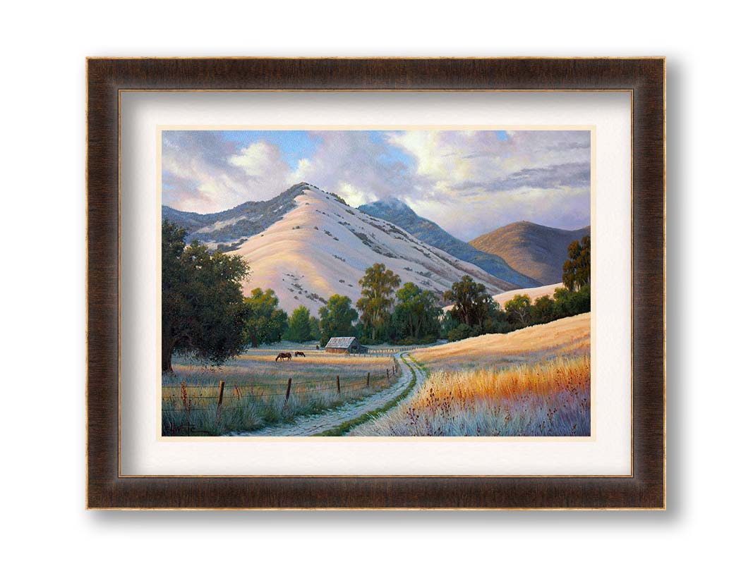 A painting of the volcanic hills of the Santa Ynez mountains from the perspective of the valley below. Clouds cast blue shadows between the light on the golden grasses of a field where horses graze. The mountain range reaches up through low clouds in the distance. Printed on paper, matted, and framed.