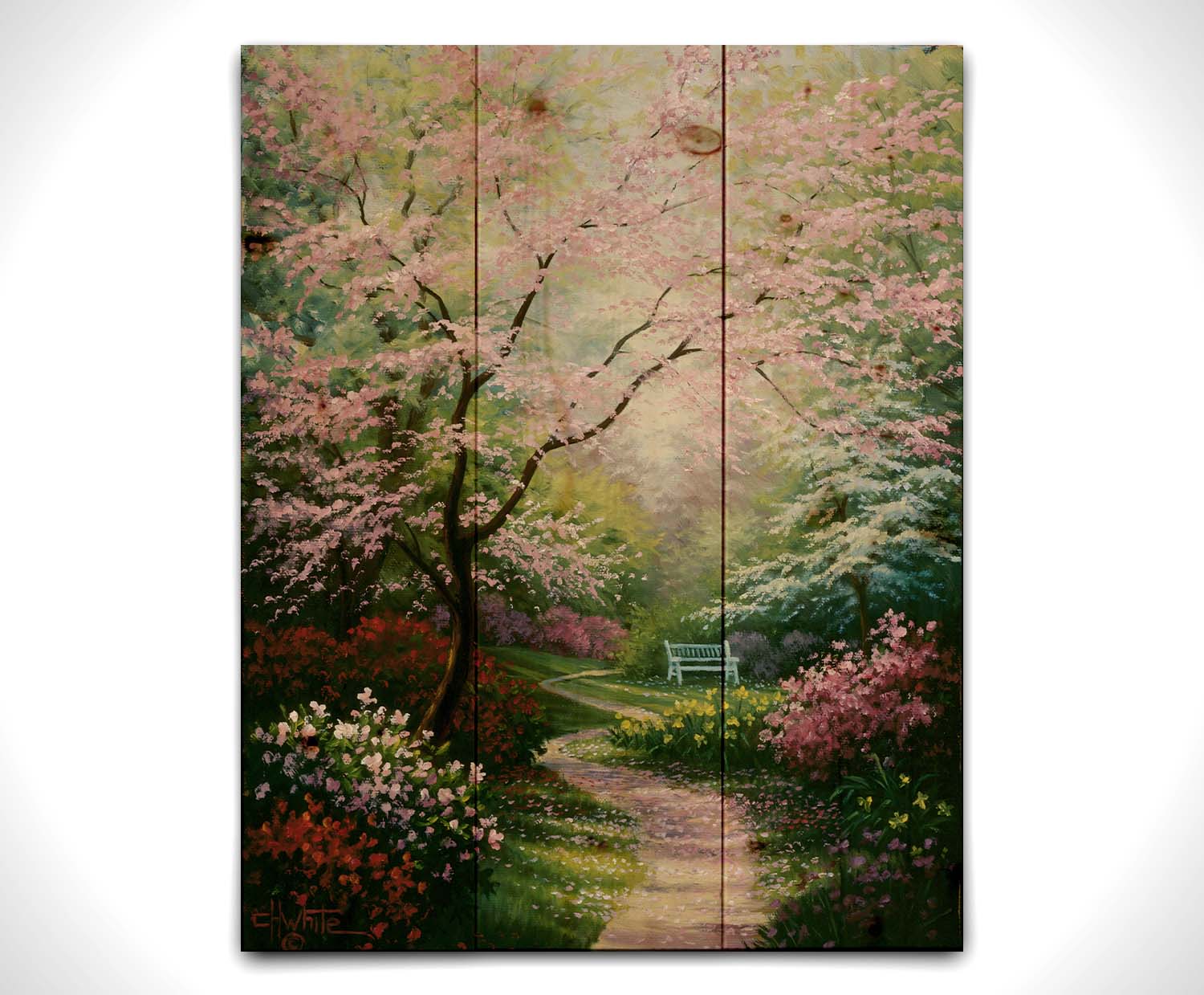 A painting of a garden in spring, with pink, red, and white blossoms on the bushes and trees. Pink petals fall from a tree by the narrow path, piling on the ground. A park bench can be seen in the distance. Printed on a wood pallet.