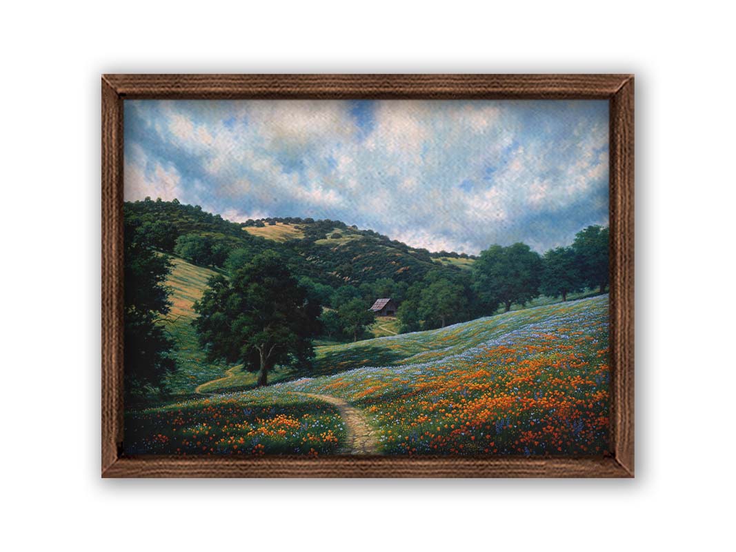 A painting of a hillside meadow of orange and blue flowers. A thin dirt path cuts through the meadow, leading to an old barn in the distance. Printed on canvas and framed.