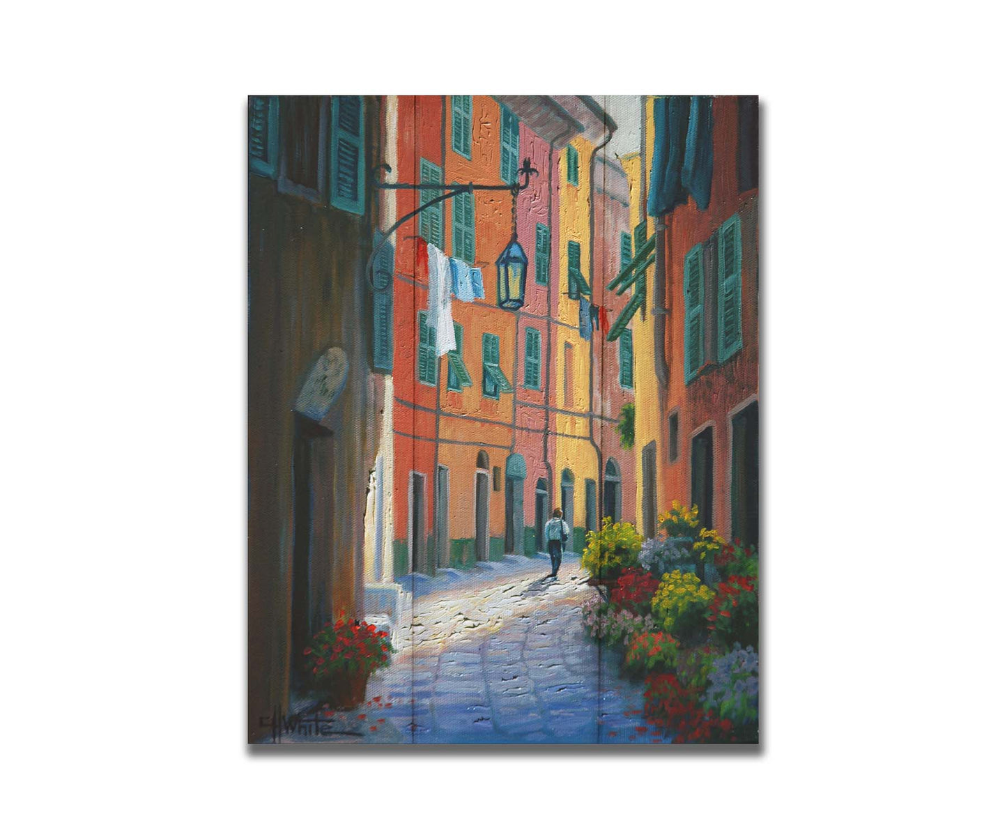 A painting of a stone path through Portofino, Italy. Warm-colored building line the road, clothes hanging from their window lines. Potted flowers grow at the doorsteps. Printed on a box board.