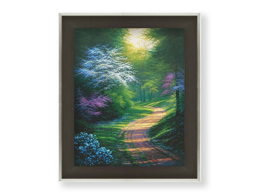 A painting of a dirt path through a wooded area during spring. Trees lining the road bloom in pink and white. Small yellow flowers dot the grass around the path. Printed on canvas and framed.