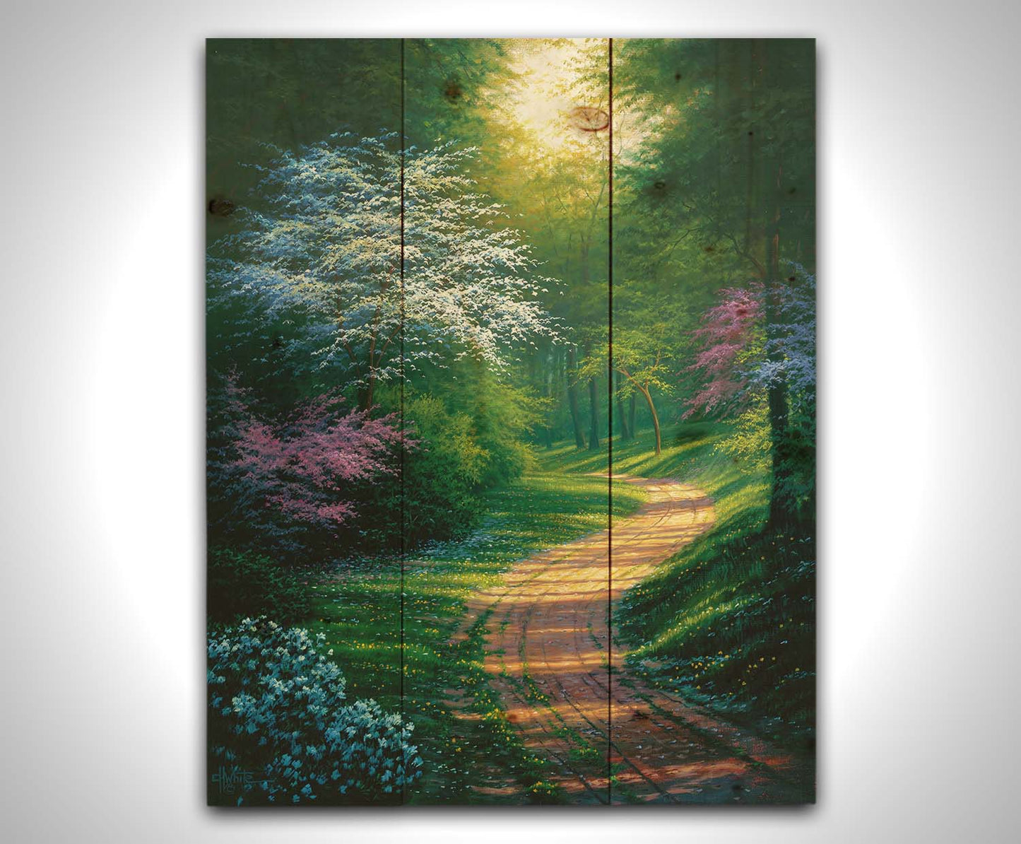 A painting of a dirt path through a wooded area during spring. Trees lining the road bloom in pink and white. Small yellow flowers dot the grass around the path. Printed on a wood pallet.