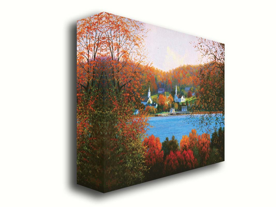 A painting of a small lakeside town, surrounded by an autumn forest. Orange and red leaves contrast green grass and vibrant blue water. Printed on canvas.