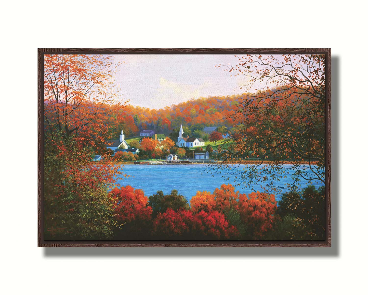 A painting of a small lakeside town, surrounded by an autumn forest. Orange and red leaves contrast green grass and vibrant blue water. Printed on canvas in a float frame.