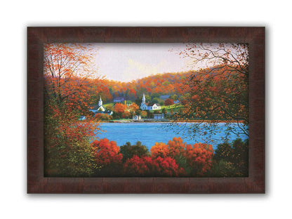 A painting of a small lakeside town, surrounded by an autumn forest. Orange and red leaves contrast green grass and vibrant blue water. Printed on canvas and framed.