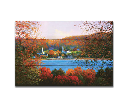 A painting of a small lakeside town, surrounded by an autumn forest. Orange and red leaves contrast green grass and vibrant blue water. Printed on a box board.