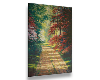 A painting of a dirt path through a spring woodland. Vibrant green trees grow alongside red japanese maples and pink and white blossoms. Printed on metal.