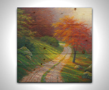 A painting of a gravel road winding around a hill between autumn trees. Printed on a wood pallet.