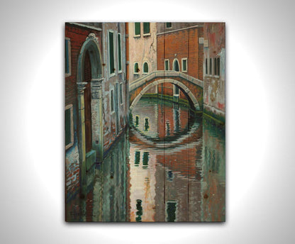 A painting of a Venice canal alleyway, passing under a bridge between old brick buildings. Printed on a wood pallet.