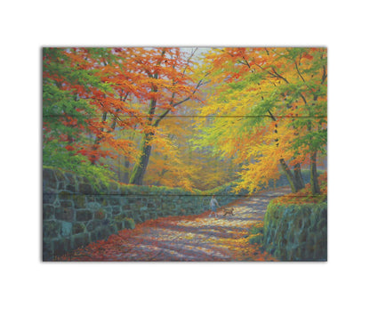 A painting of a stone road through a forest. It is bordered by stone walls on either side. The leaves of the trees are changing colors and dropping to the ground for fall. A person can be seen walking a leashed down further down the path. Printed on a box board.