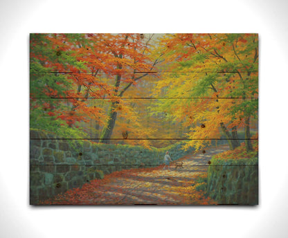 A painting of a stone road through a forest. It is bordered by stone walls on either side. The leaves of the trees are changing colors and dropping to the ground for fall. A person can be seen walking a leashed down further down the path. Printed on a wood pallet.