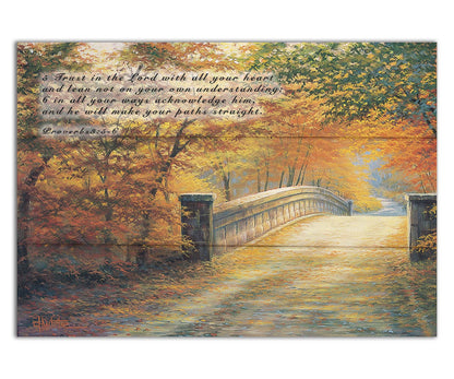 A painting looking down a bridge road during fall. The trees lining the road have turned yellow and orange for autumn, and some of their fallen leaves are scatted along the path. It is overlayed in the upper left with Proverbs 3:5-6 of the Bible, reading "5. Trust in the Lord with all your heart and lean not on your own understanding; 6. In all your ways acknowledge him, and he will make your paths straight." Printed on a box board.