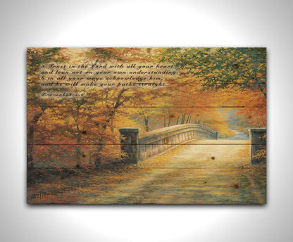 A painting looking down a bridge road during fall. The trees lining the road have turned yellow and orange for autumn, and some of their fallen leaves are scatted along the path. It is overlayed in the upper left with Proverbs 3:5-6 of the Bible, reading "5. Trust in the Lord with all your heart and lean not on your own understanding; 6. In all your ways acknowledge him, and he will make your paths straight." Printed on a wood pallet.