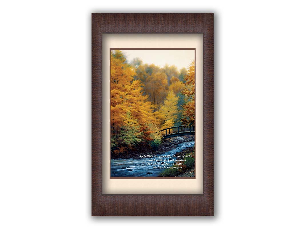 A painting of a forest stream, passing under an arched bridge. The trees are changing to yellow and orange for the fall season. The bottom right corner is overlaid with Psalm 1:3 in the Bible, reading "Psalm 1:3 from the Bible, reading "He is like a tree planted by streams of water, which yields its fruit in season and whose leaf does not wither. Whatever he does prospers." Printed on paper, matted, and framed.