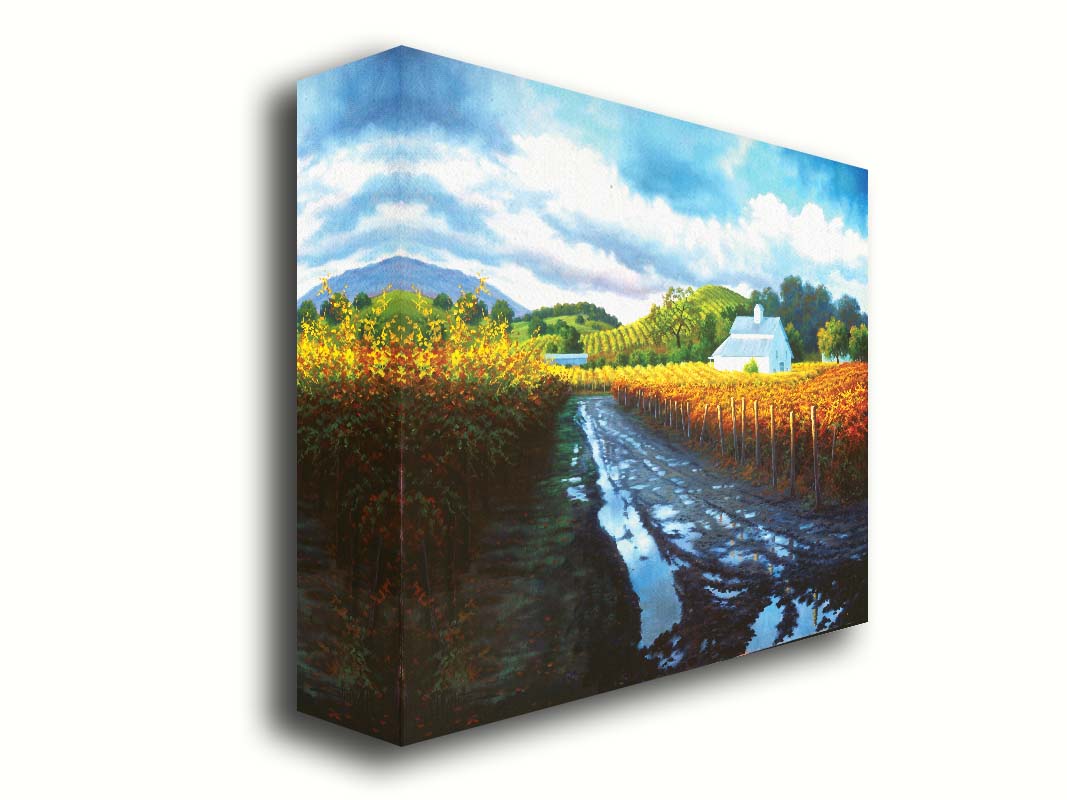 A painting looking down a road puddled with water. On either side, orange, red, and yellow grape vines grow in the vineyard. White barns and houses sit between the fields. Printed on canvas.