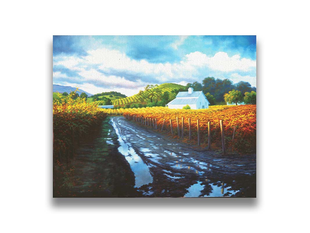 A painting looking down a road puddled with water. On either side, orange, red, and yellow grape vines grow in the vineyard. White barns and houses sit between the fields. Printed on canvas.