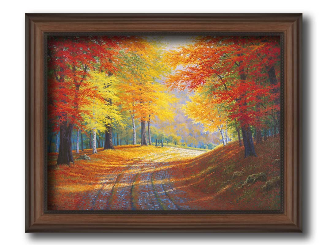 A painting of a gravel road through a forest in autumn. Orange red, and yellow leaves coat the ground and cover the trees, highlighted by bright sunlight. Printed on canvas and framed.