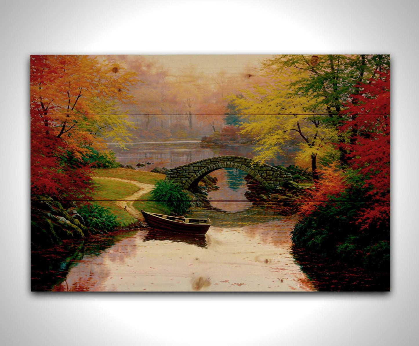 A painting of an idyllic fall scene, with colorful maples surrounding a river crossed by a small stone bridge. A rowboat is tied down near the bridge. Printed on a wood pallet.