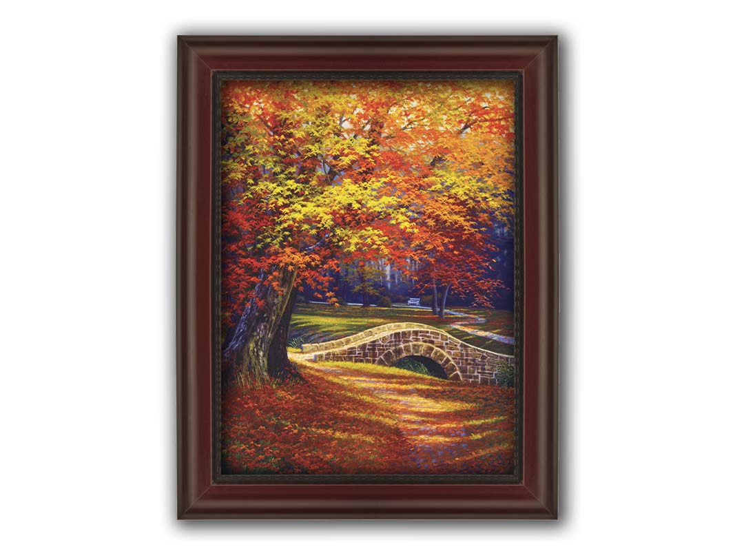 A painting of an autumn park, with the colorful trees dropping orange leaves onto the path below. A stone bridge crosses a small stream. Printed on canvas and framed.