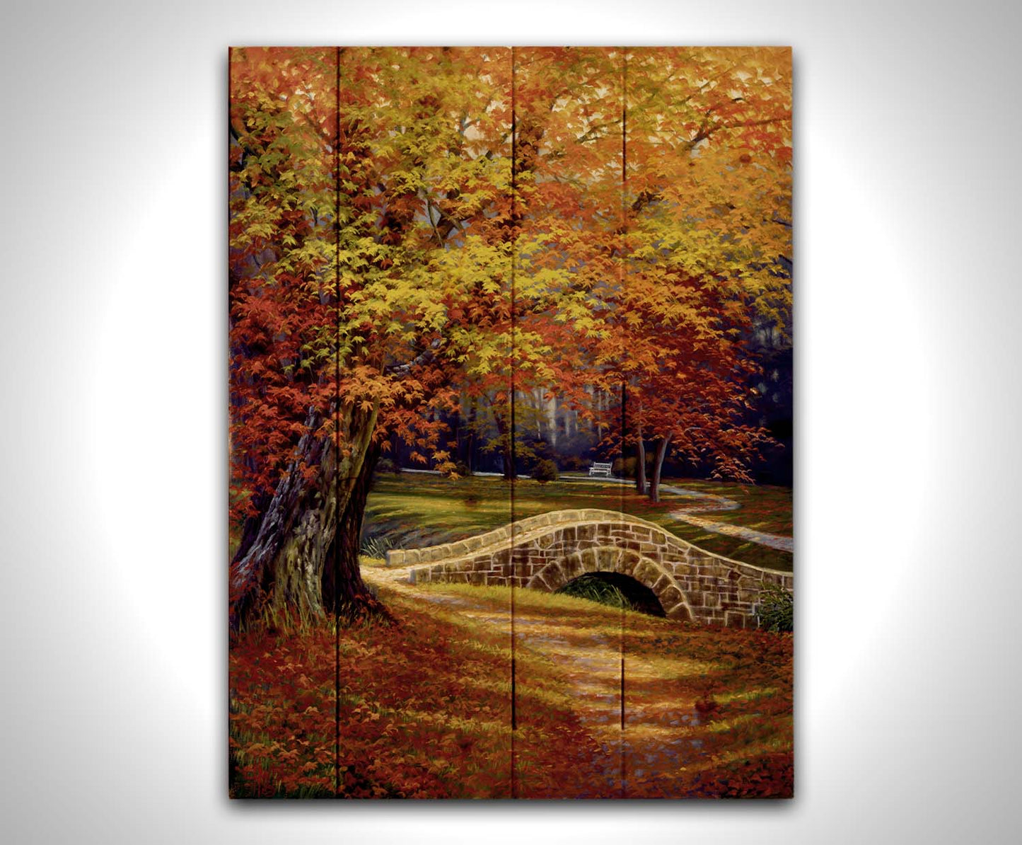 A painting of an autumn park, with the colorful trees dropping orange leaves onto the path below. A stone bridge crosses a small stream. Printed on a wood pallet.