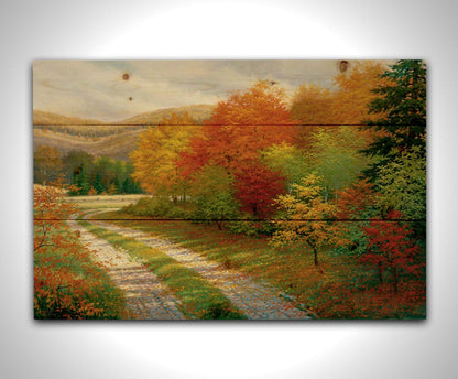 A painting of a forest in autumn, cut through by a gravel road curving into the distant fields and hills. Printed on a wood pallet.