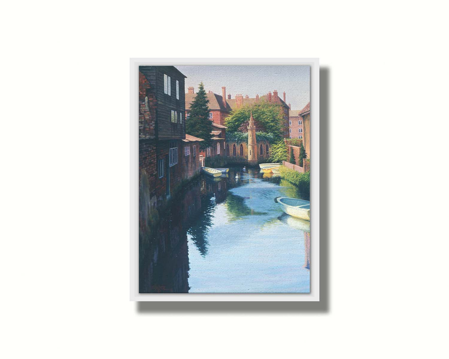 A painting of a canal in Canterbury in Kent, England. A few small row boats are docked along the waterway between historic red brick buildings. Printed on canvas in a float frame.