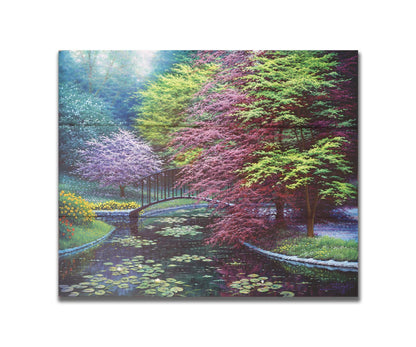 A painting of a peaceful garden pond covered in lily pads, and surrounded by vibrant red and yellow flowers, striking red maples, and blossoming white and pink trees. Printed on a box board.